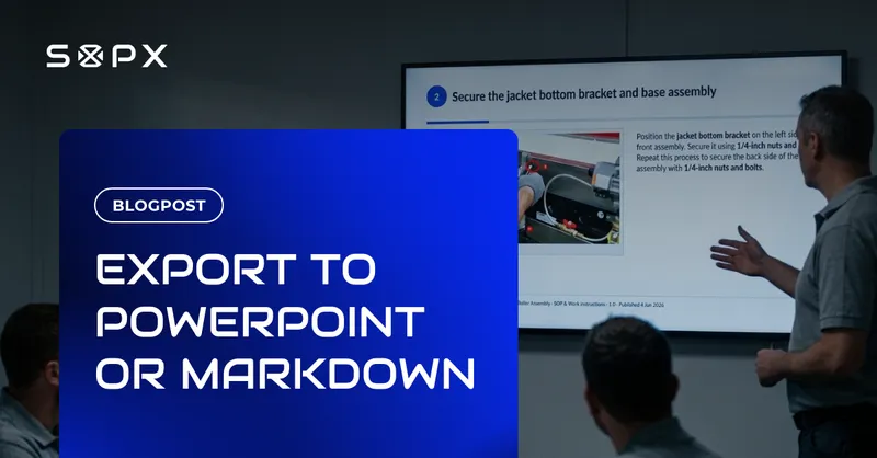 A supervisor seen from behind presenting an exported SOP slide on a wall display to a small group of seated workers in a meeting room.
