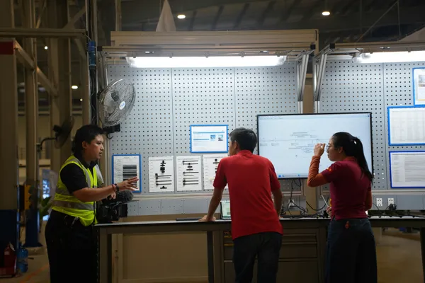 Supervisor giving work instructions as part of job training to a group of workers.